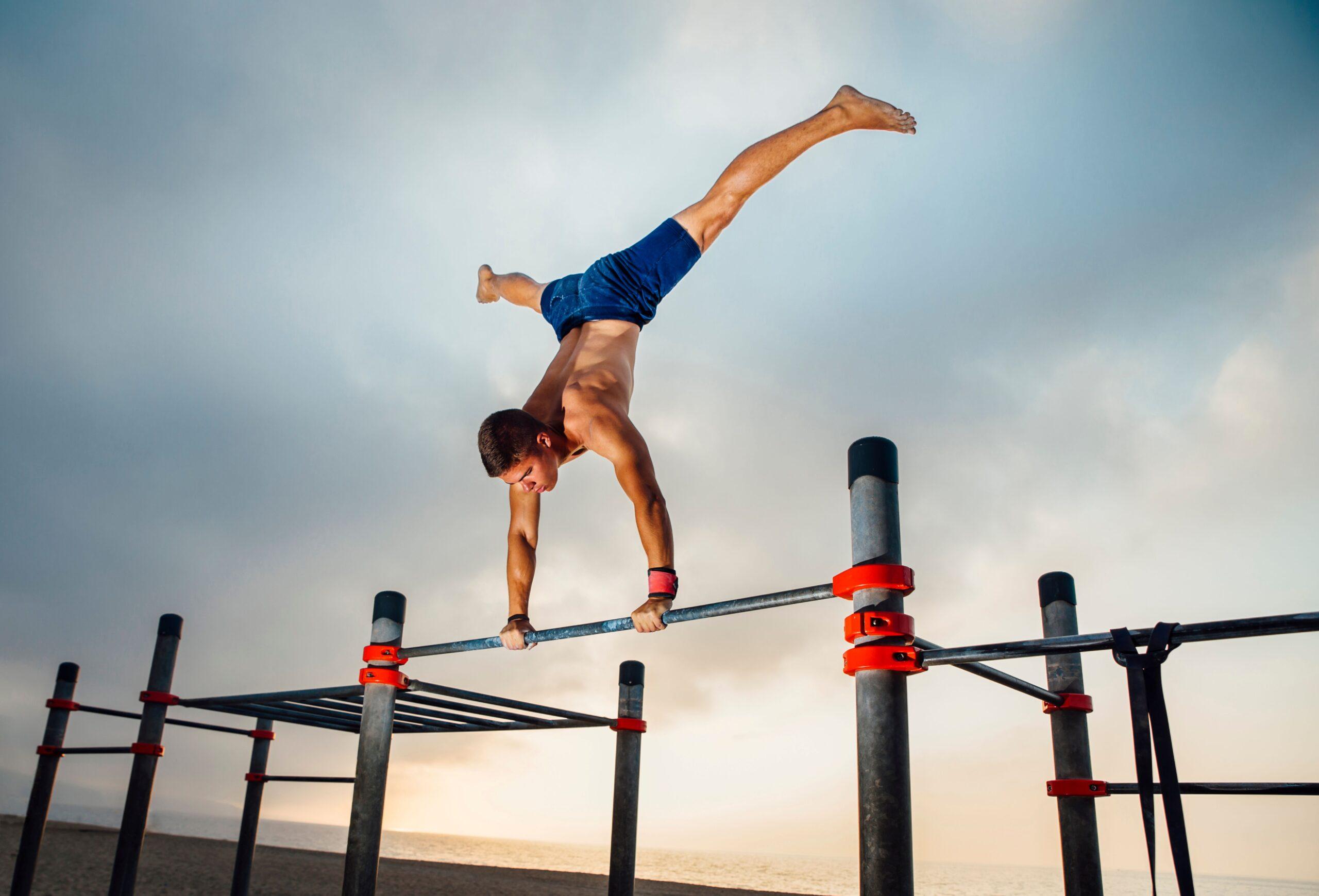 Sportler zeigt eine Handstand-Variation auf einer Calisthenics-Stange