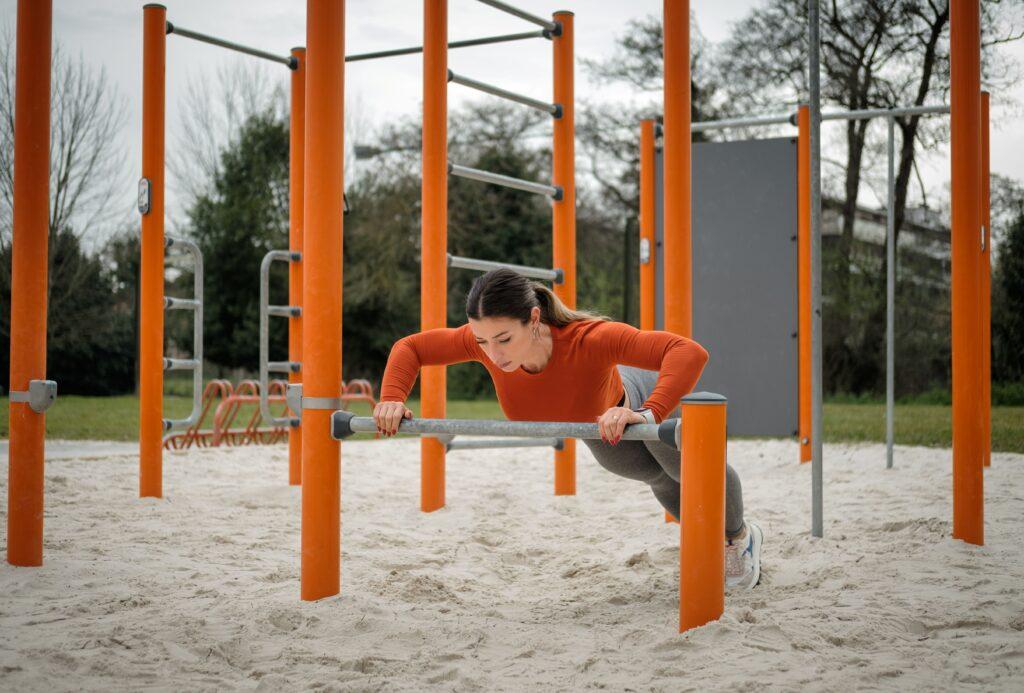 Frau trainiert an einer Calisthenics-Station im Freien