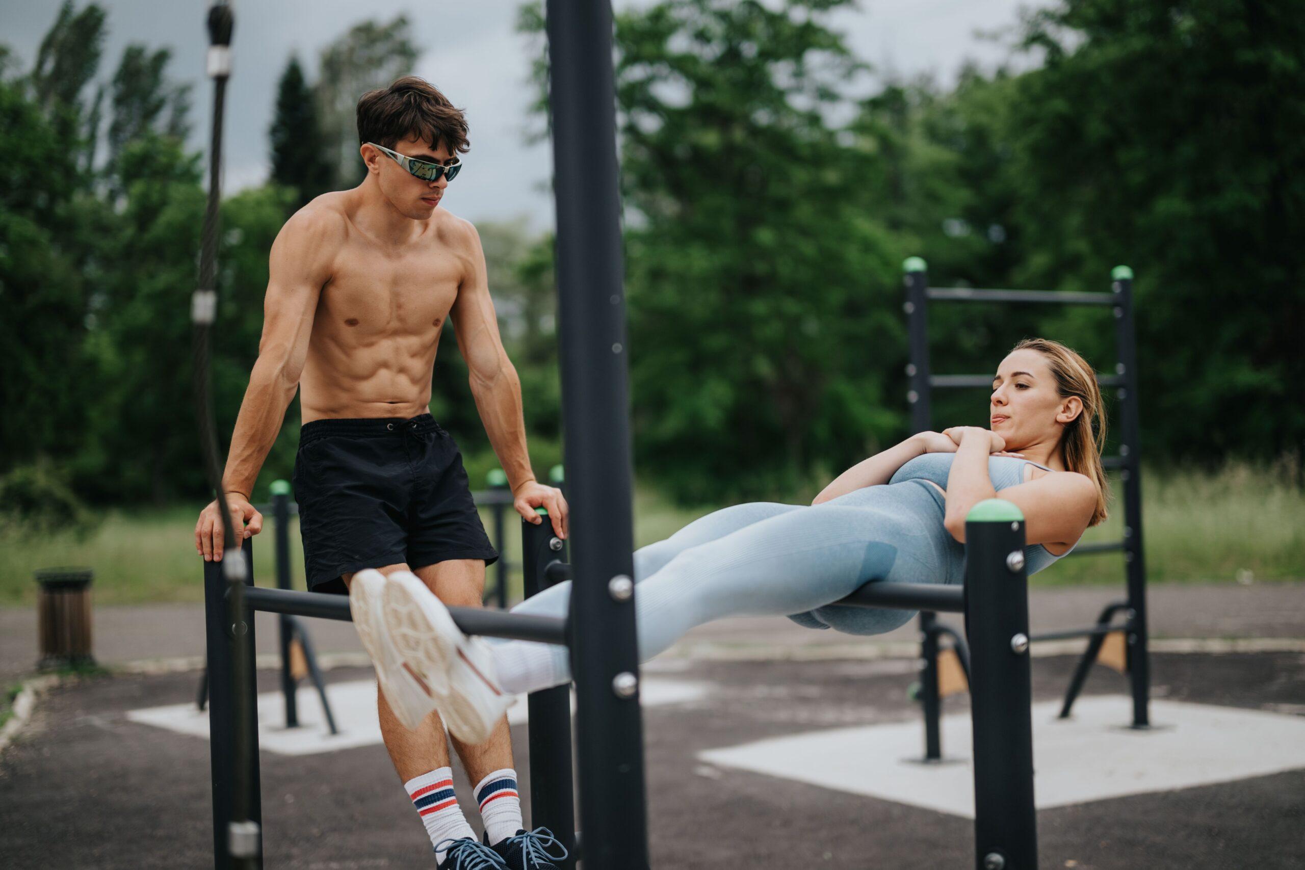 Ein sportliches Paar trainiert an einer Calisthenics-Station im Freien