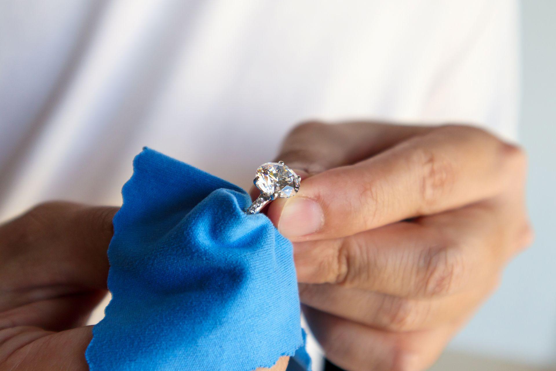 ringpflege mit blauem tuch hand reinigt schmuckstueck mit diamant